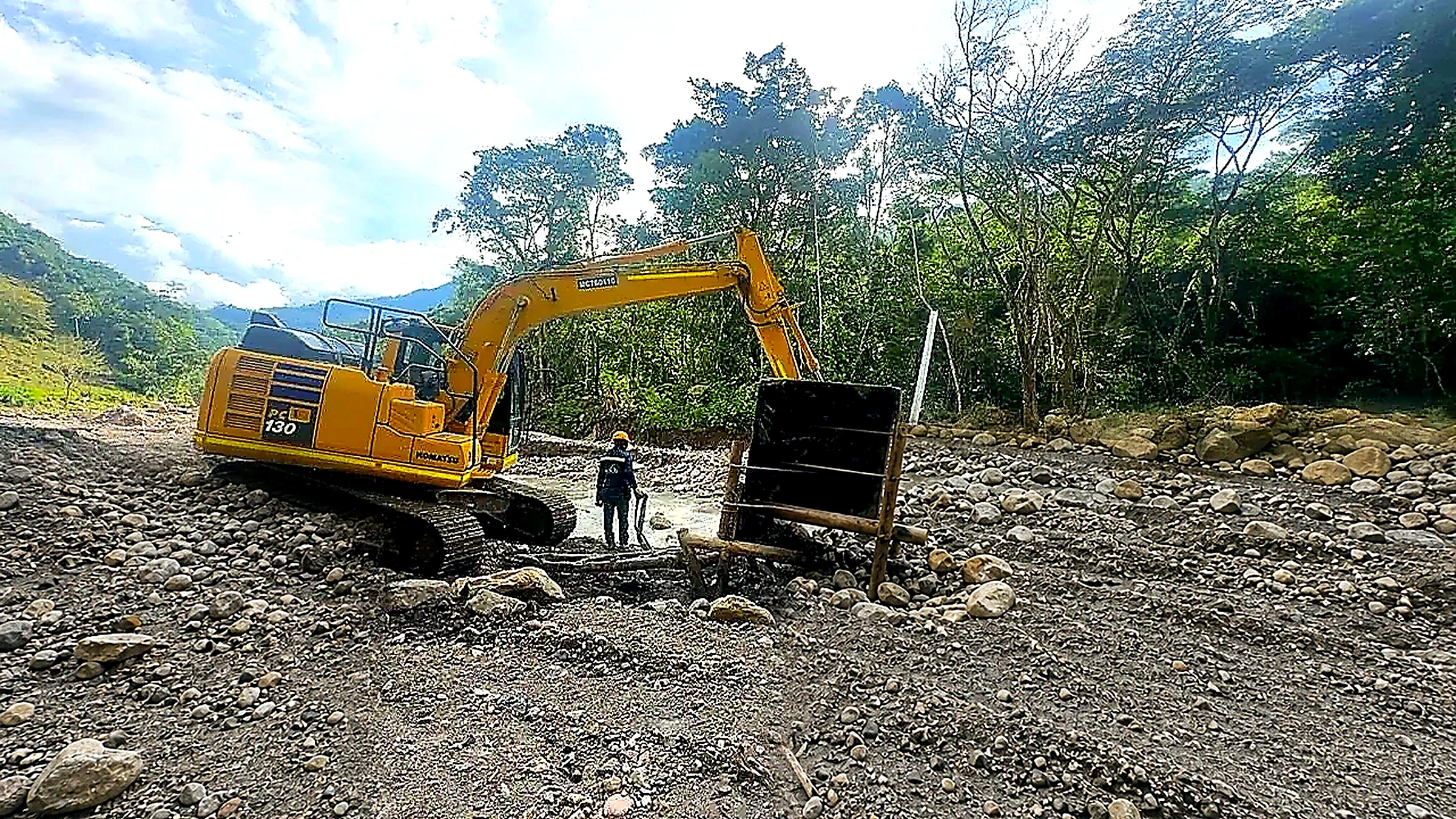 Excavadora trabajando en un cauce junto a estructura de protección